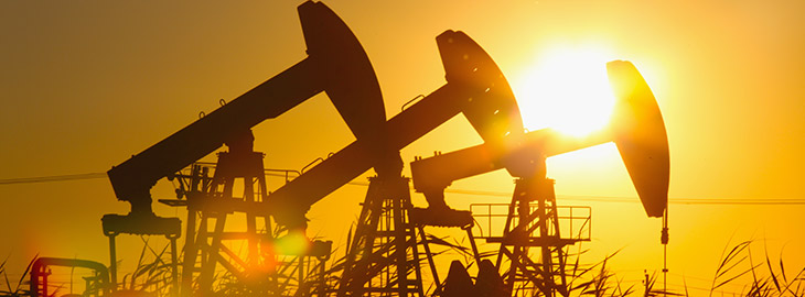 sunlight shining through a row of oil derricks