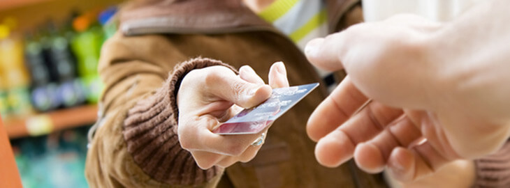 female handing her credit card to a grocery checkout clerk