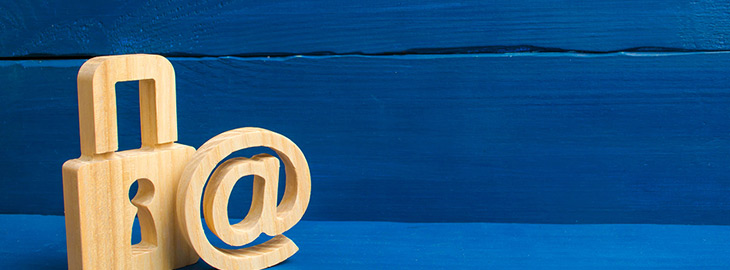 wooden carvings of @ symbol and padlock against a blue wooden background