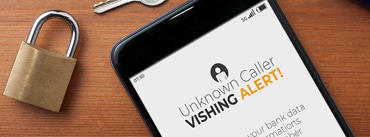 smartphone on desk displaying vishing alert on screen