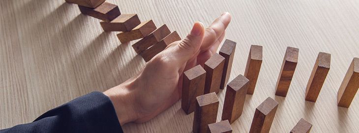 hand interrupting falling dominoes