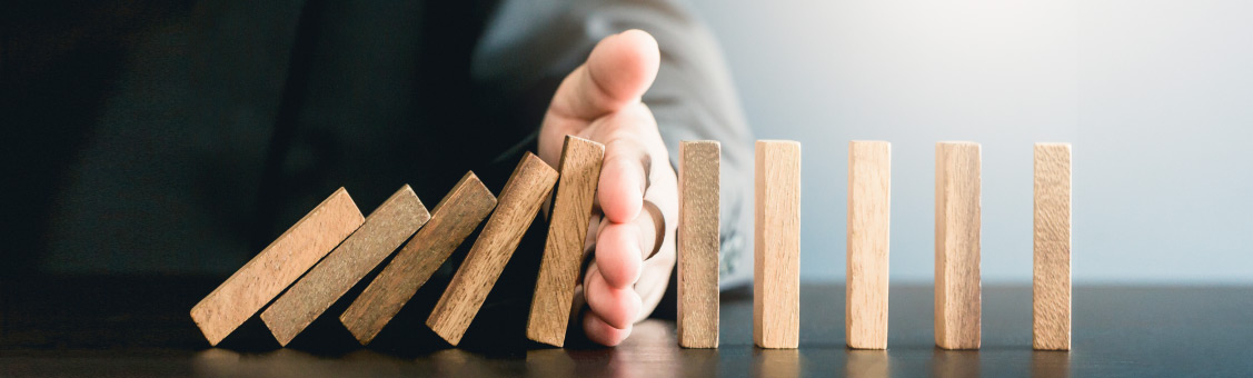 businessman stopping domino sequence with his hand